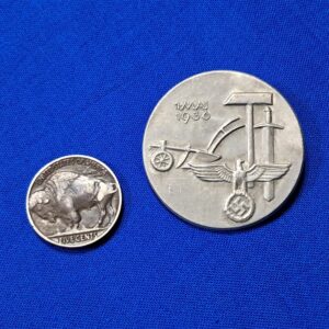 Tinnie May-day WWII 36. Condition excellent. Made of aluminum and maker marked on the reverse. Biedermann & Co. Original pin on the reverse. VERY clean with no oxidation. Never cleaned. This was a festival that celebration the planting of crops and other spring events