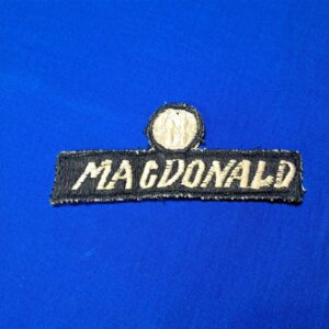 Vietnam-war-era-advisor-name-tape-with-unknown-symbol-or-rank-above-black-and-white-with-bird-in-circle