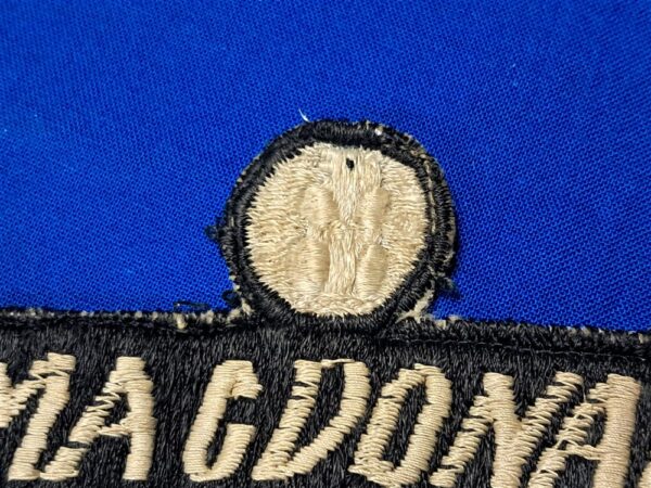Vietnam-war-era-advisor-name-tape-with-unknown-symbol-or-rank-above-black-and-white-with-bird-in-circle