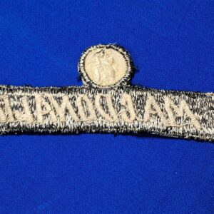 Vietnam-war-era-advisor-name-tape-with-unknown-symbol-or-rank-above-black-and-white-with-bird-in-circle